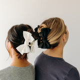 Two women wearing the Classy Chic Lilac Clips in their hair with bows.