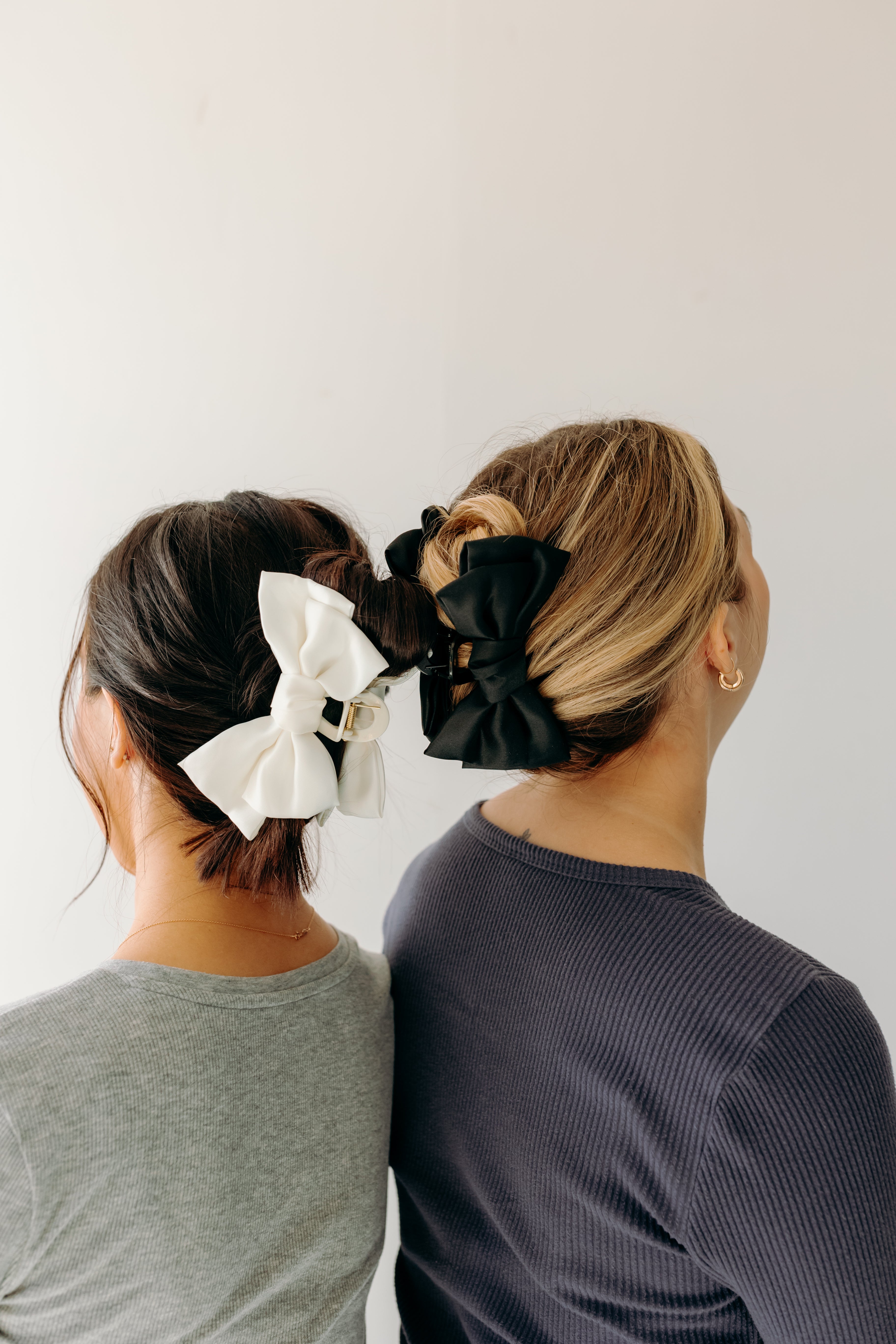 Two women wearing the Classy Chic Lilac Clips in their hair with bows.
