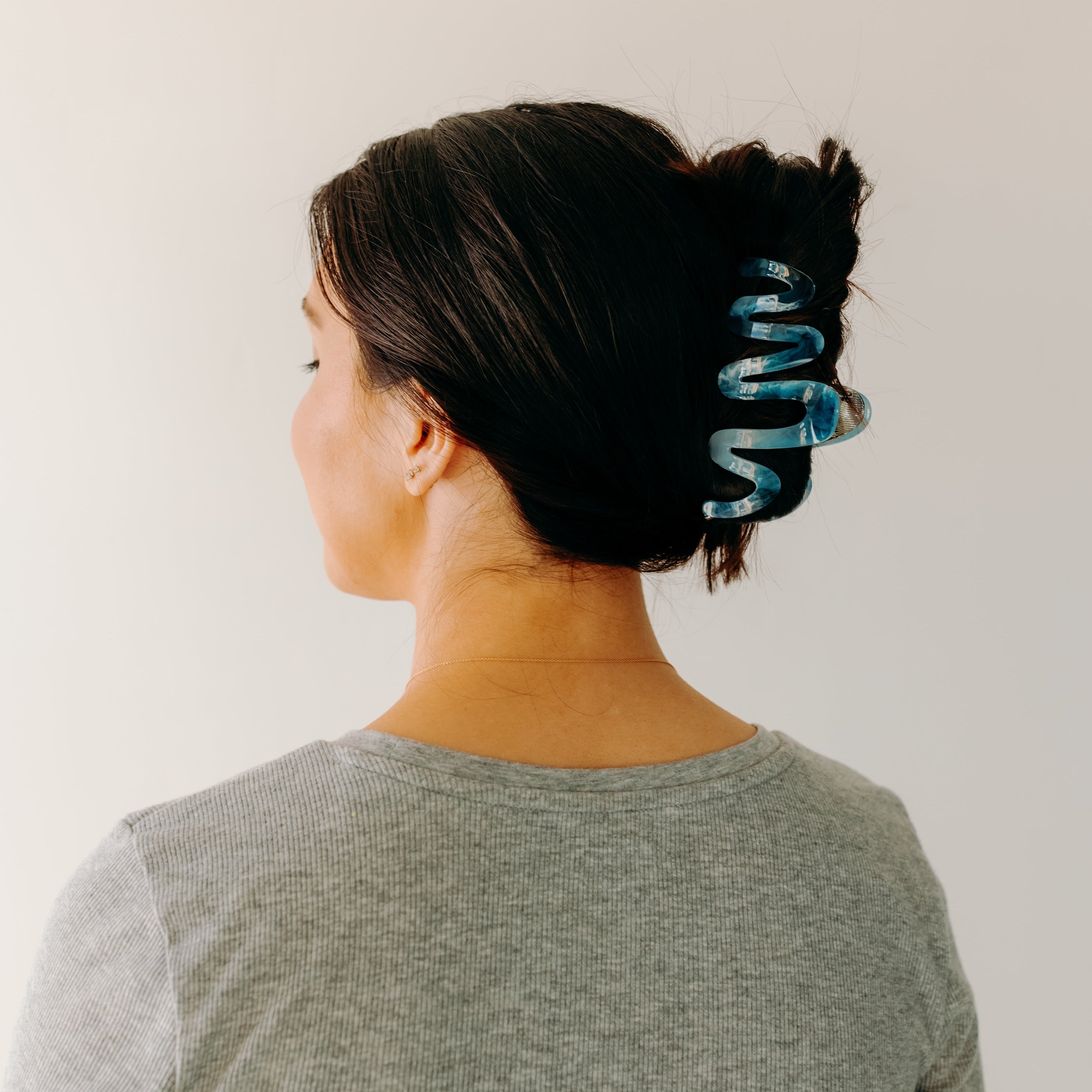 Woman wearing a dark blue Comes in Waves Lilac Clip hair clip, showcasing her hairstyle.