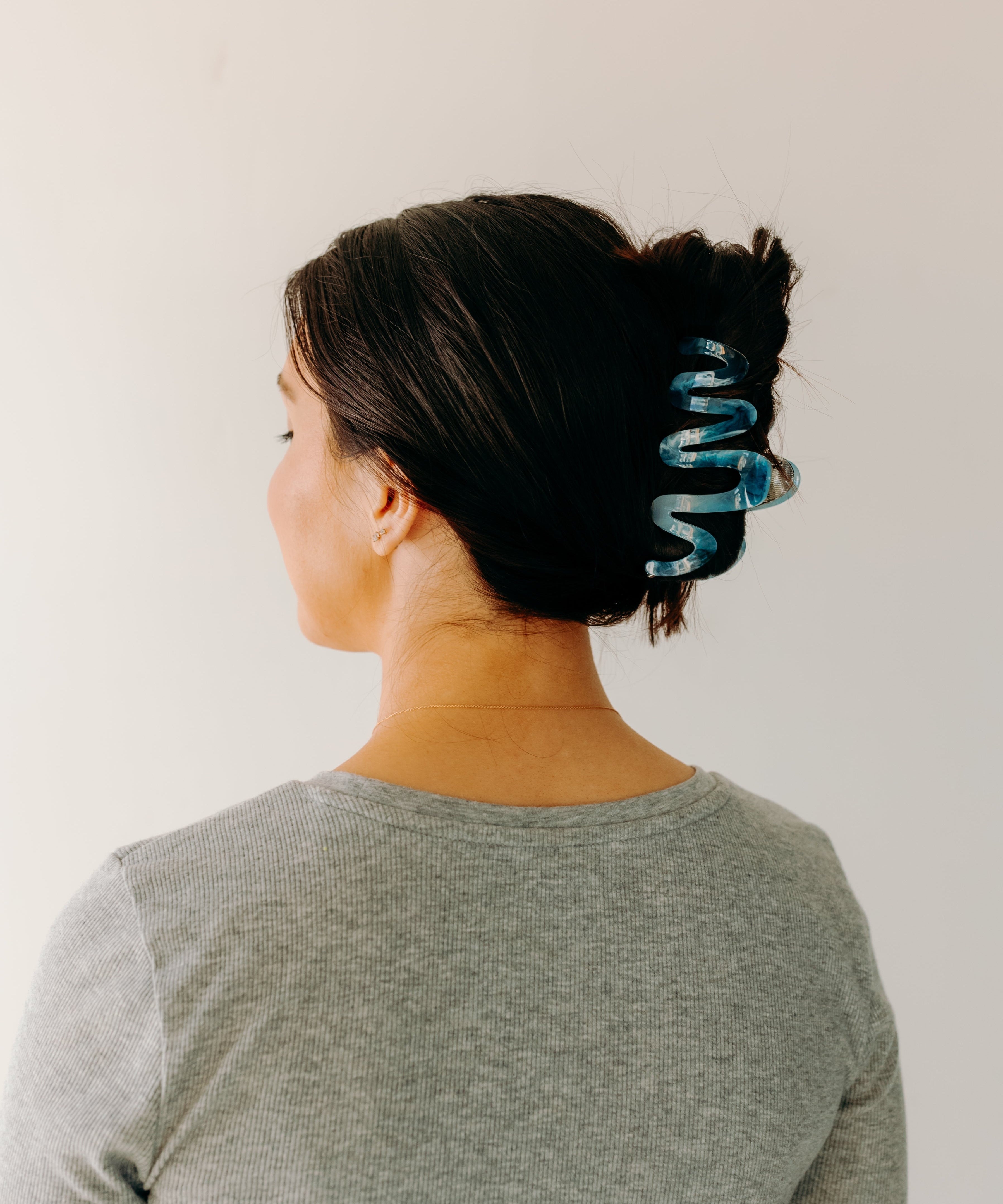 Woman wearing a dark blue Comes in Waves Lilac Clip hair clip, showcasing her hairstyle.