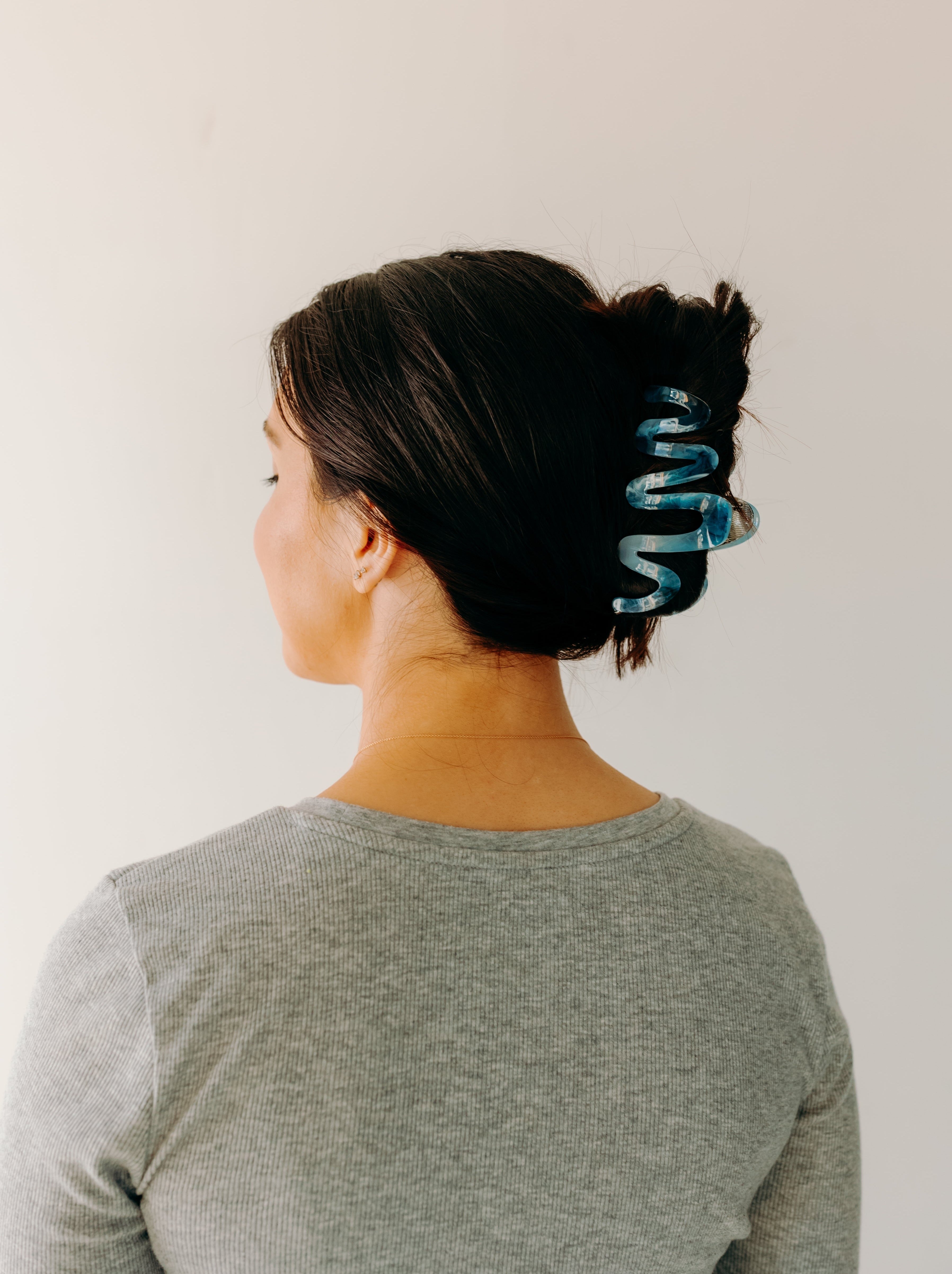 Woman wearing a dark blue Comes in Waves Lilac Clip hair clip, showcasing her hairstyle.
