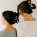 Two women wearing a dark and light blue Comes in Waves Lilac Clip hair clips, showcasing their hairstyles.