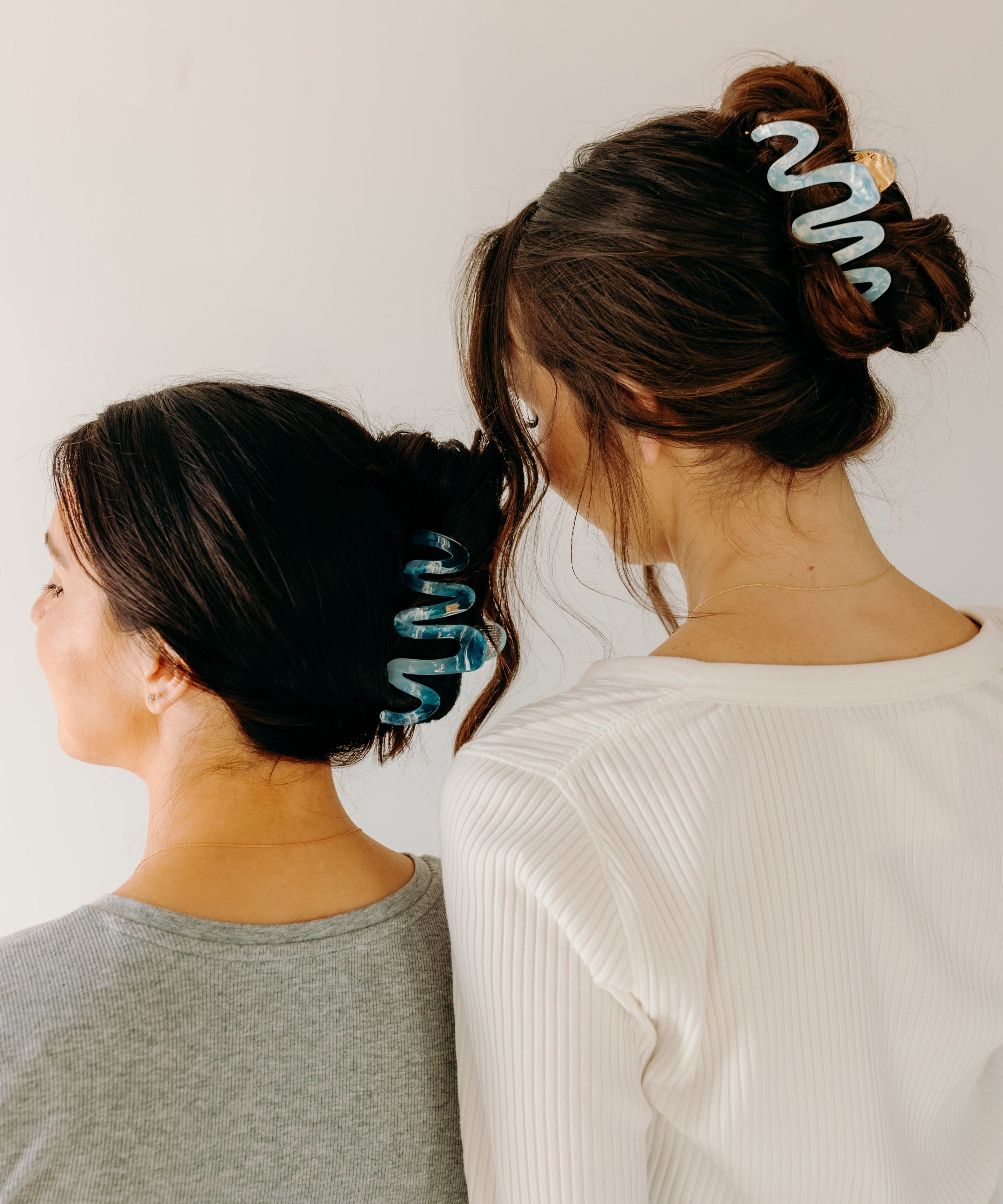 Two women wearing a dark and light blue Comes in Waves Lilac Clip hair clips, showcasing their hairstyles.
