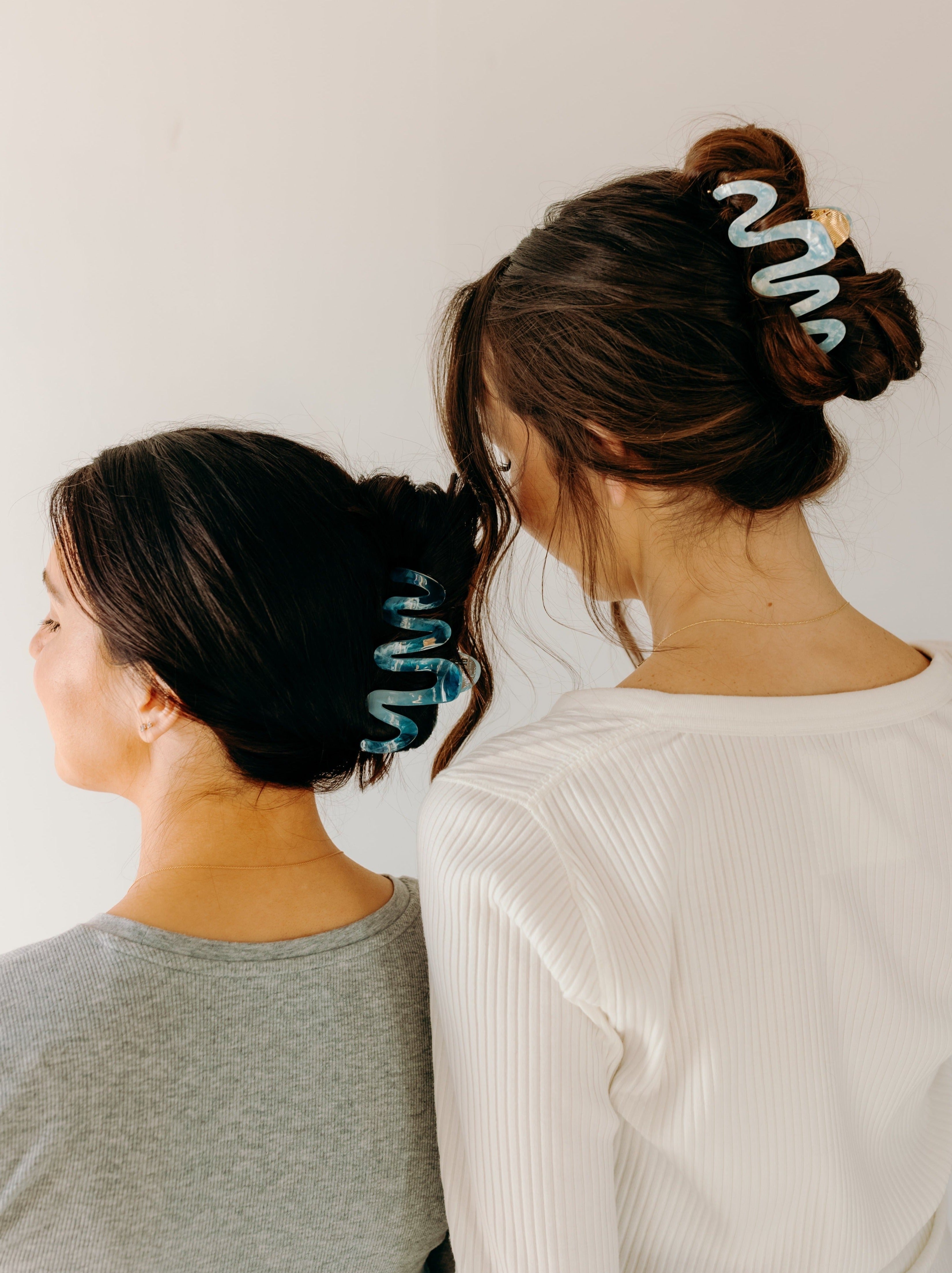 Two women wearing a dark and light blue Comes in Waves Lilac Clip hair clips, showcasing their hairstyles.
