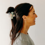Woman wearing Time to Bloom Lilac Clip in her hair, close-up of flower hair accessory.