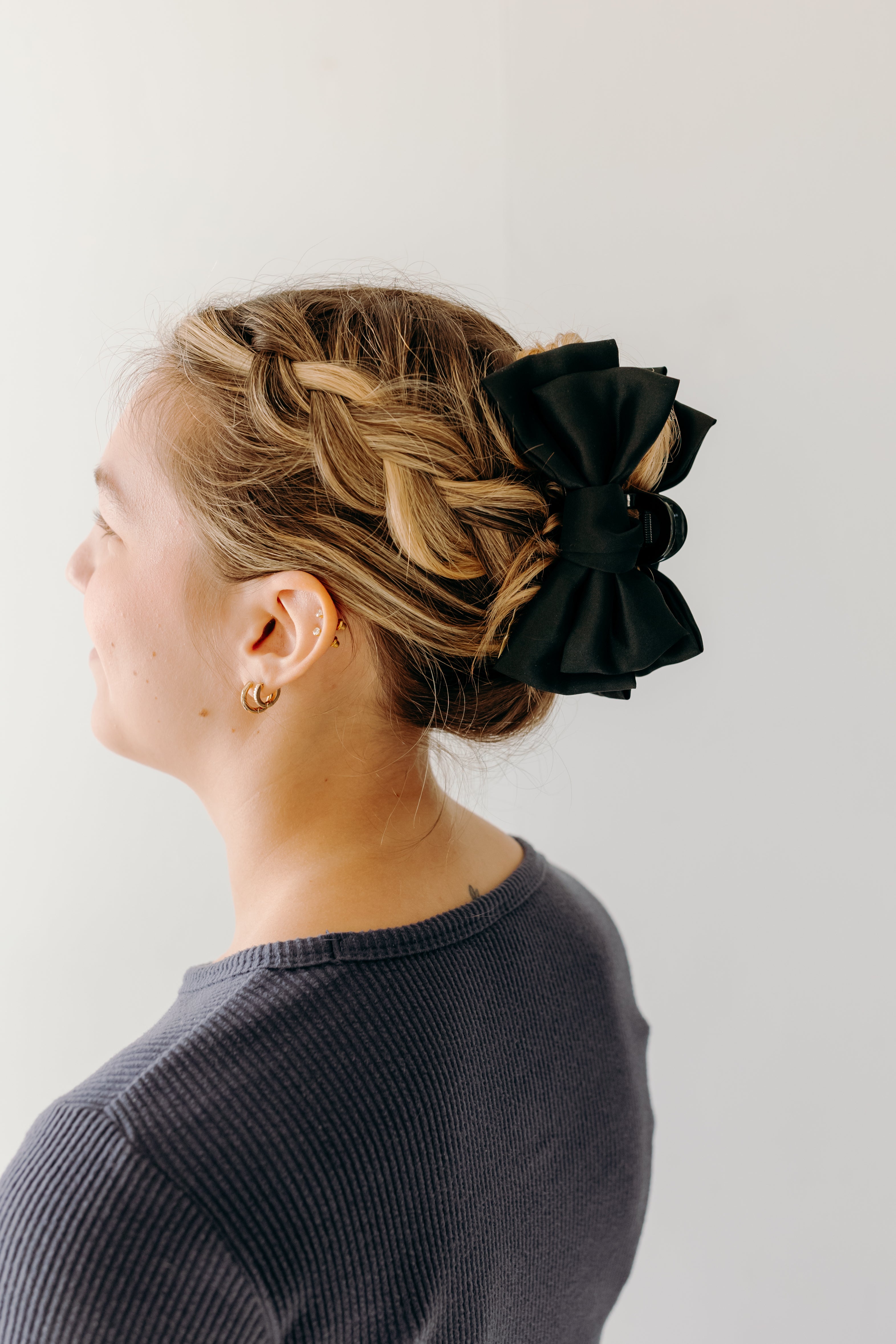 Classy Chic Lilac Clip in black adorns woman's hair with a bow.