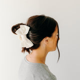 Classy Chic Lilac Clip in white adorns woman's hair with a bow.