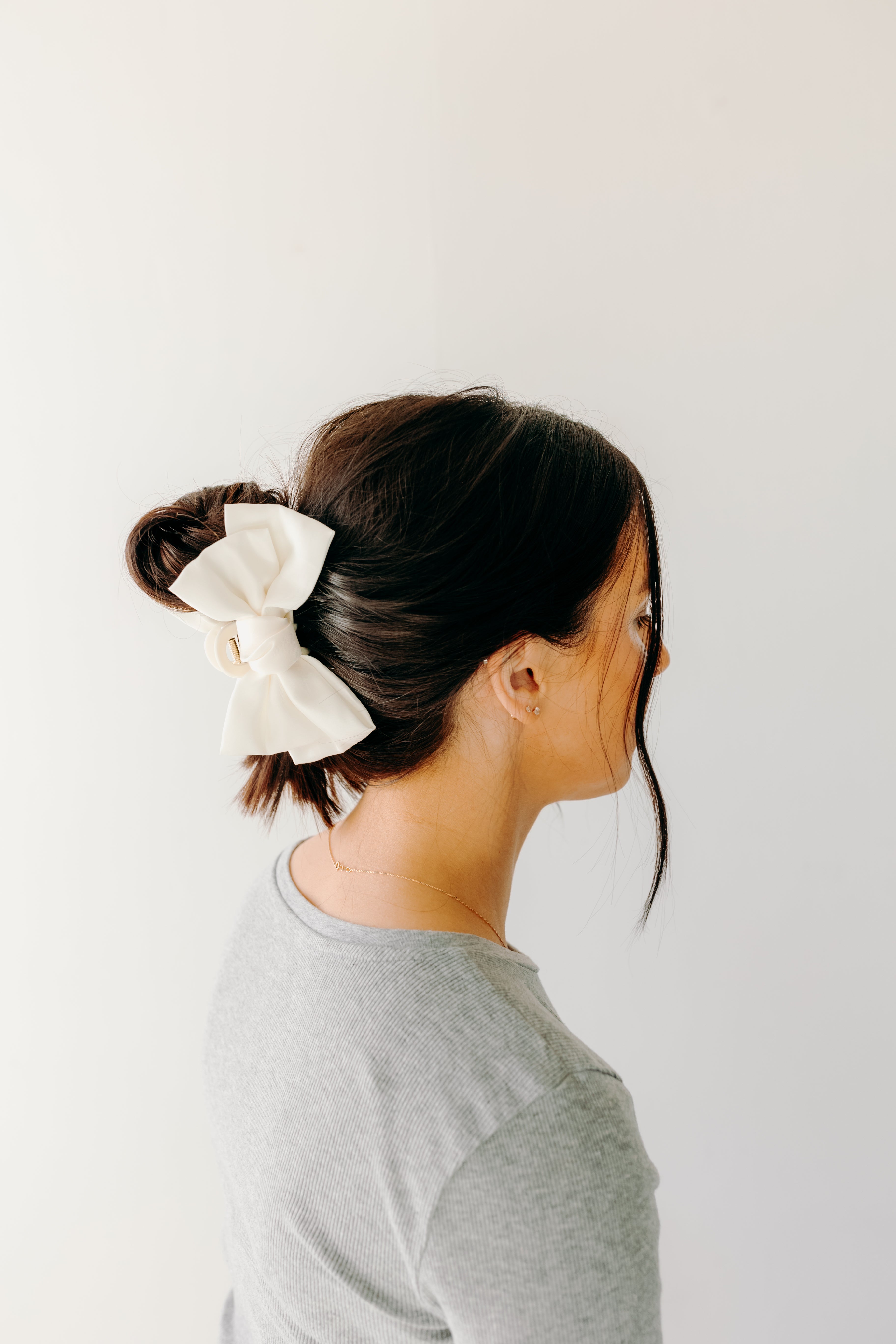 Classy Chic Lilac Clip in white adorns woman's hair with a bow.