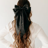 A woman wearing A Thousand Wishes Lilac Clip in her hair, with a black bow accessory.