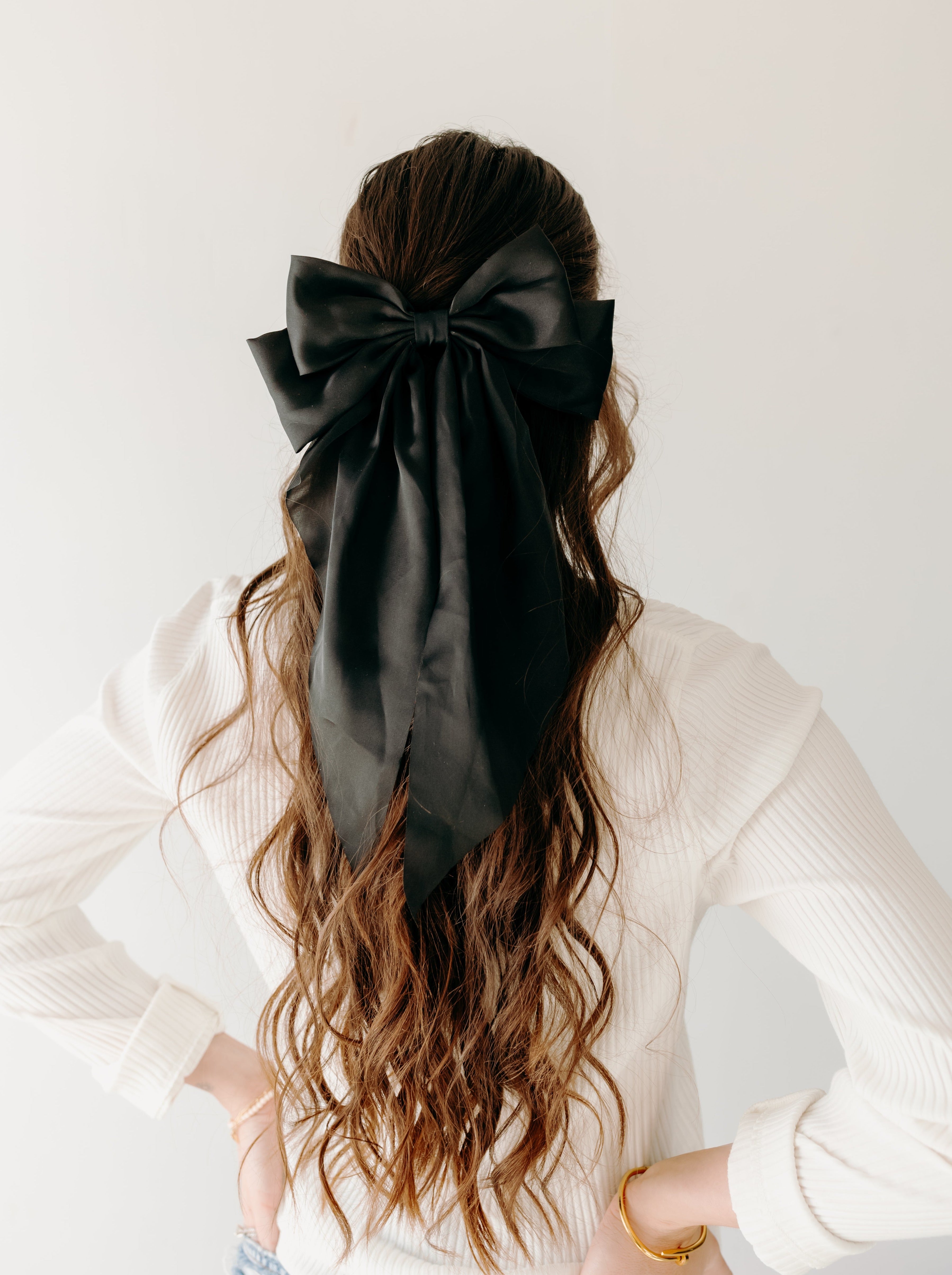 A woman wearing A Thousand Wishes Lilac Clip in her hair, with a black bow accessory.