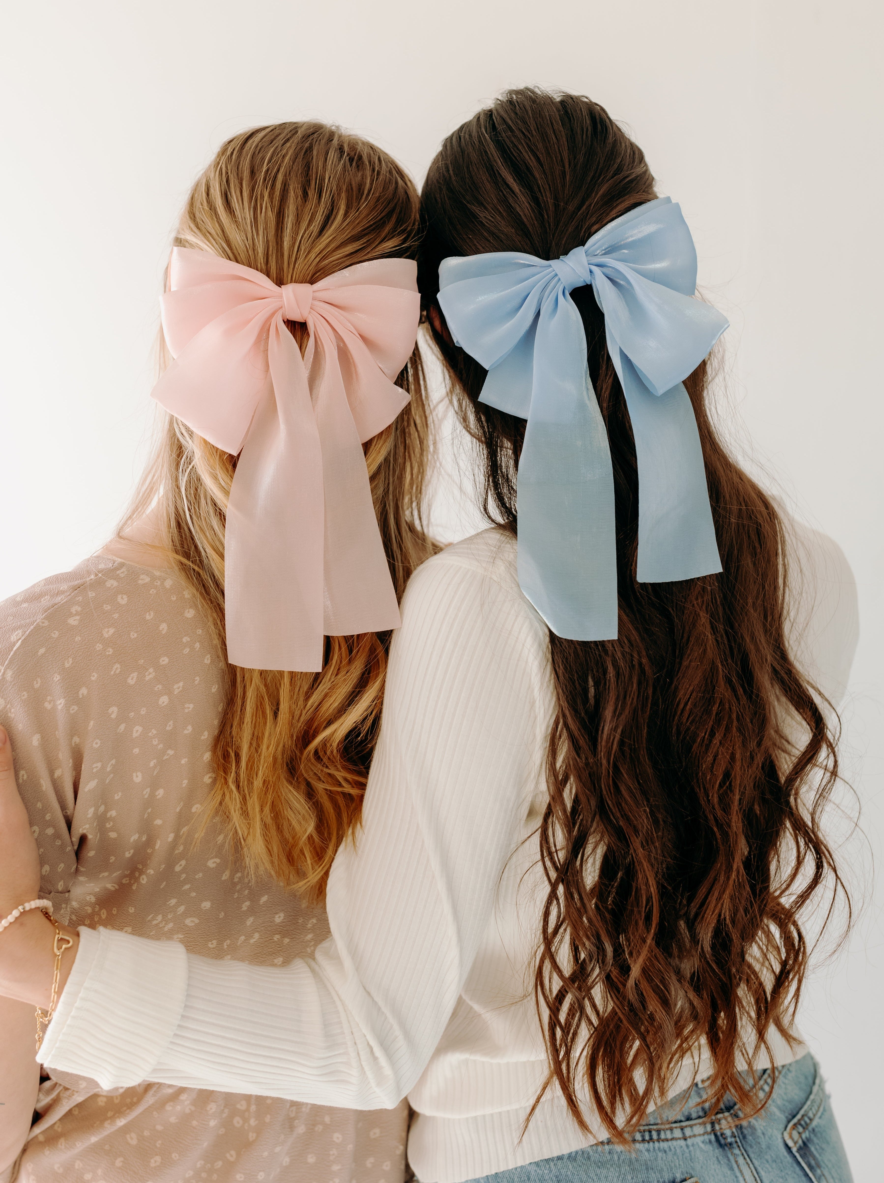 Women wearing Say Less Lilac Clips, a cute hair bow fashion accessory.