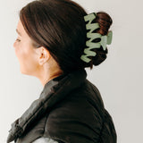 A woman with long hair showcasing the Simply Twisted Lilac Clip. Matte material, 5.5 inches long, with a hinge closure.