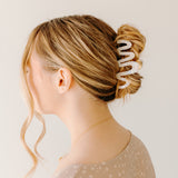 Woman wearing a white Comes in Waves Lilac Clip hair clip, showcasing her hairstyle.