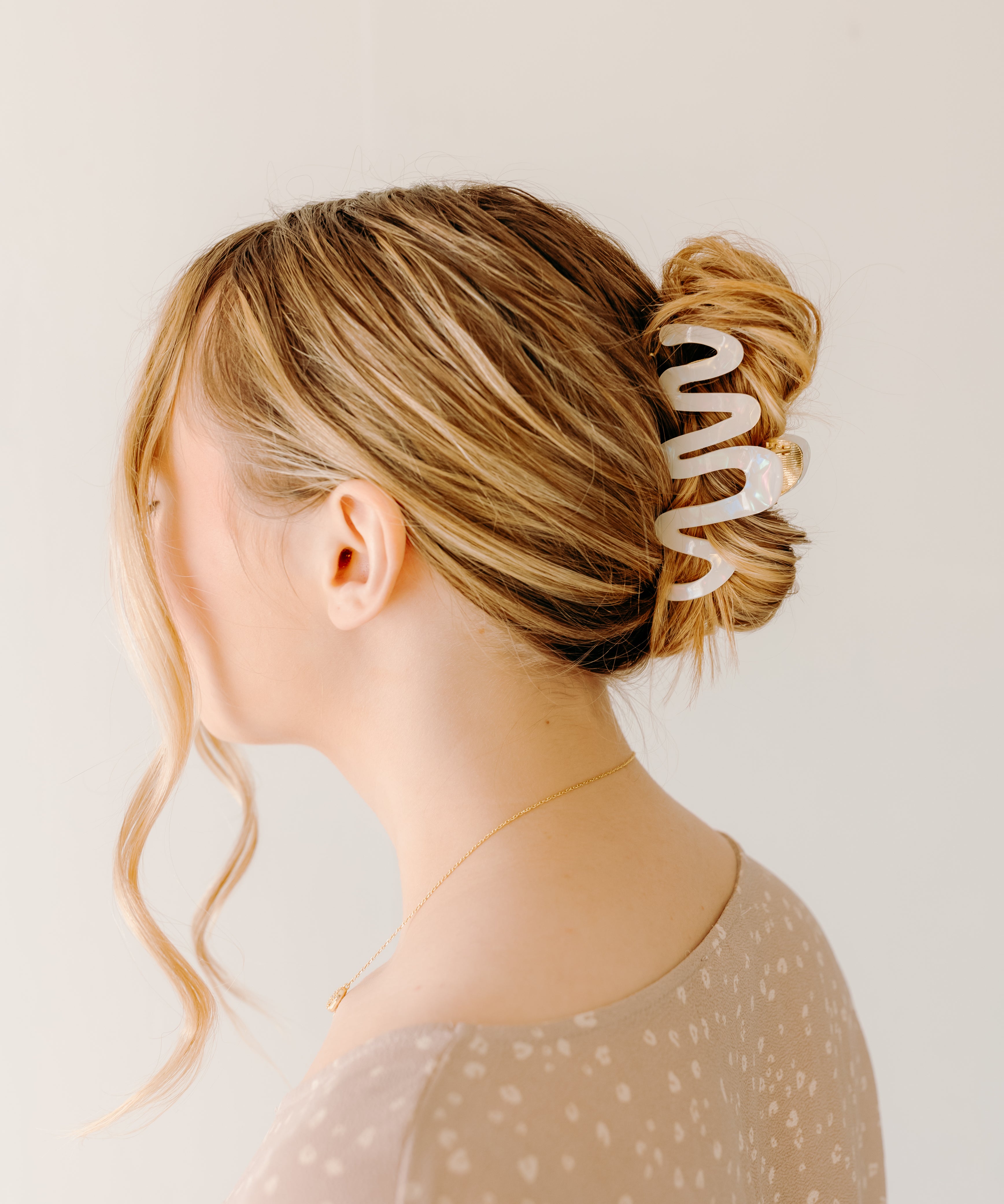 Woman wearing a white Comes in Waves Lilac Clip hair clip, showcasing her hairstyle.