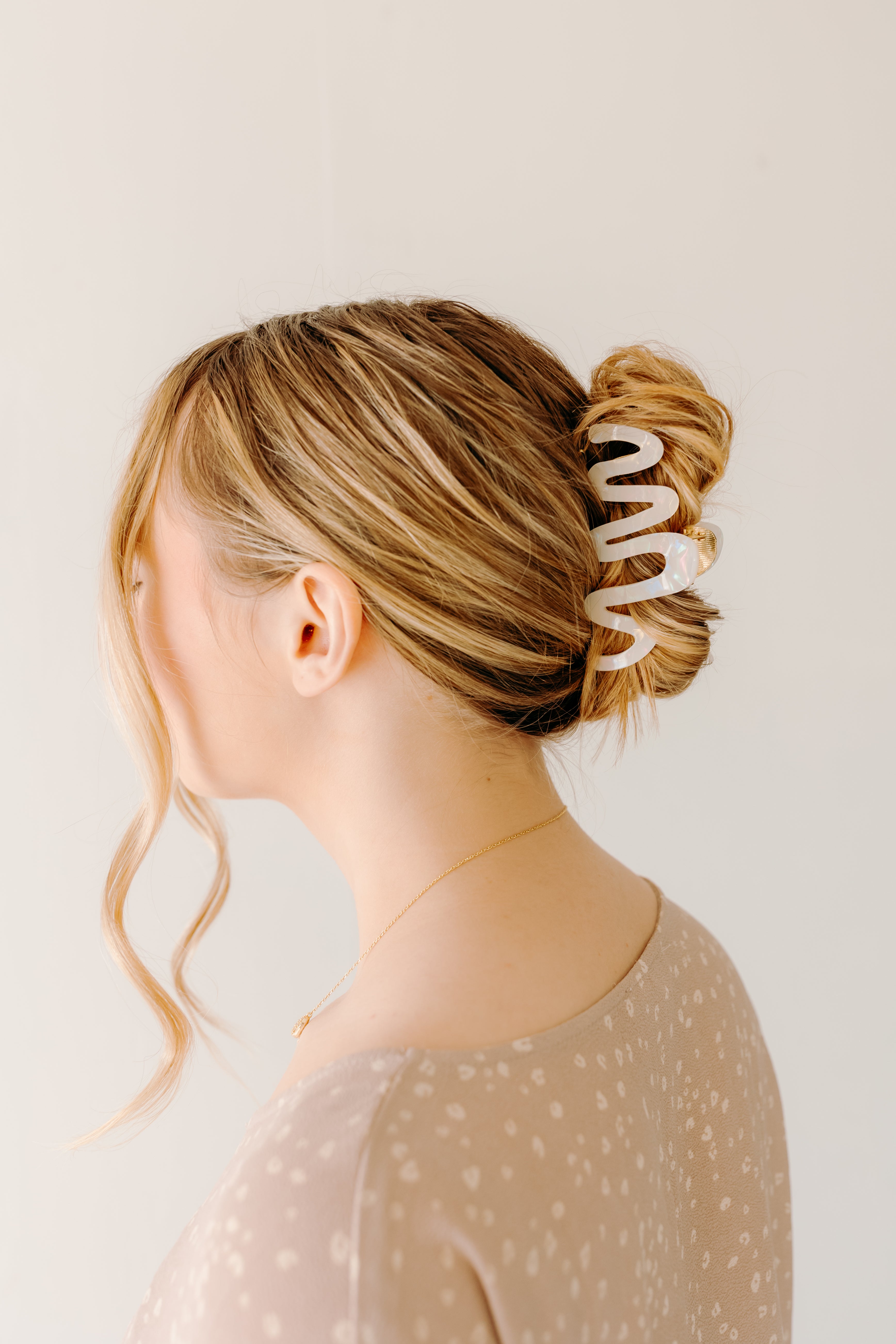 Woman wearing a white Comes in Waves Lilac Clip hair clip, showcasing her hairstyle.