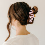 Woman wearing a pink Comes in Waves Lilac Clip hair clip, showcasing her hairstyle.