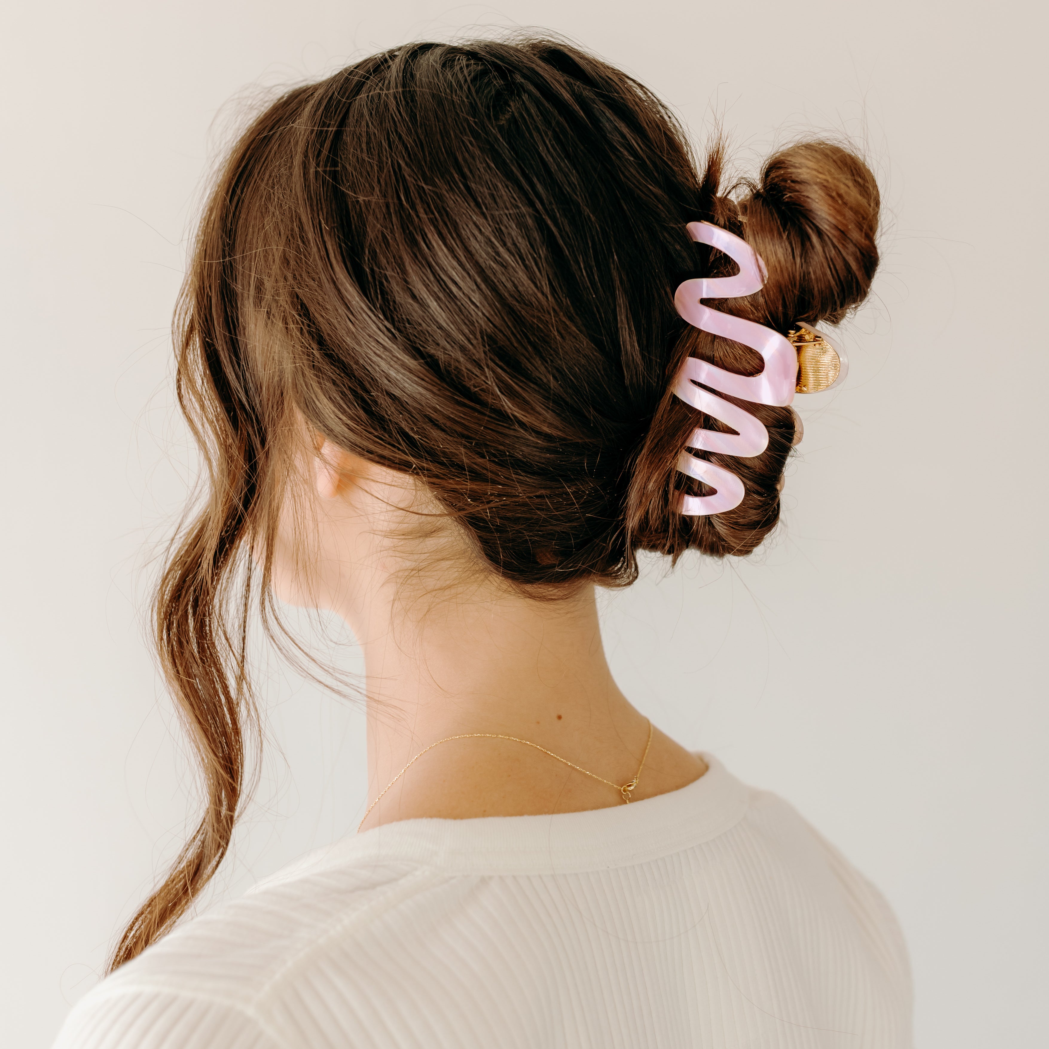 Woman wearing a pink Comes in Waves Lilac Clip hair clip, showcasing her hairstyle.