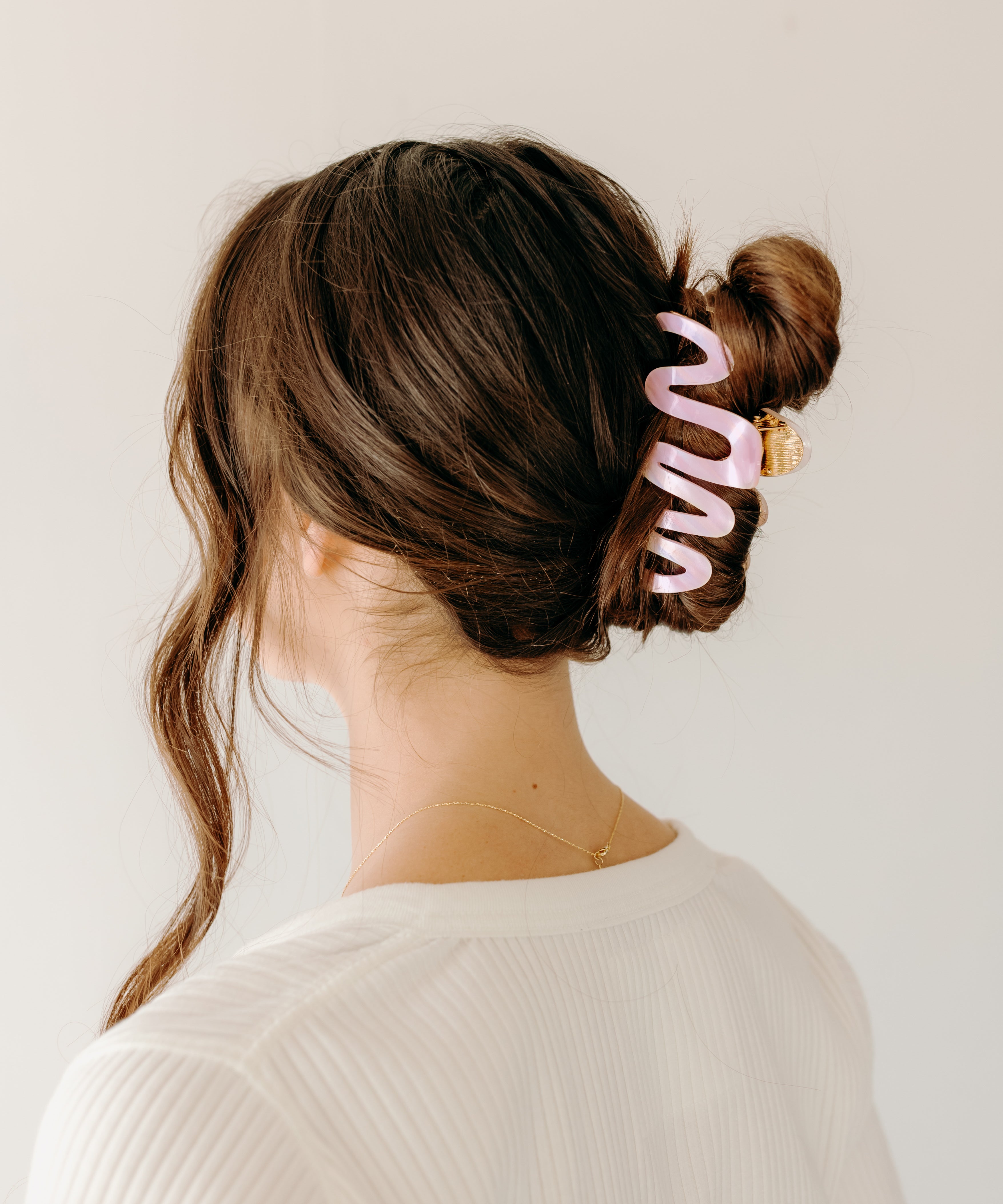 Woman wearing a pink Comes in Waves Lilac Clip hair clip, showcasing her hairstyle.