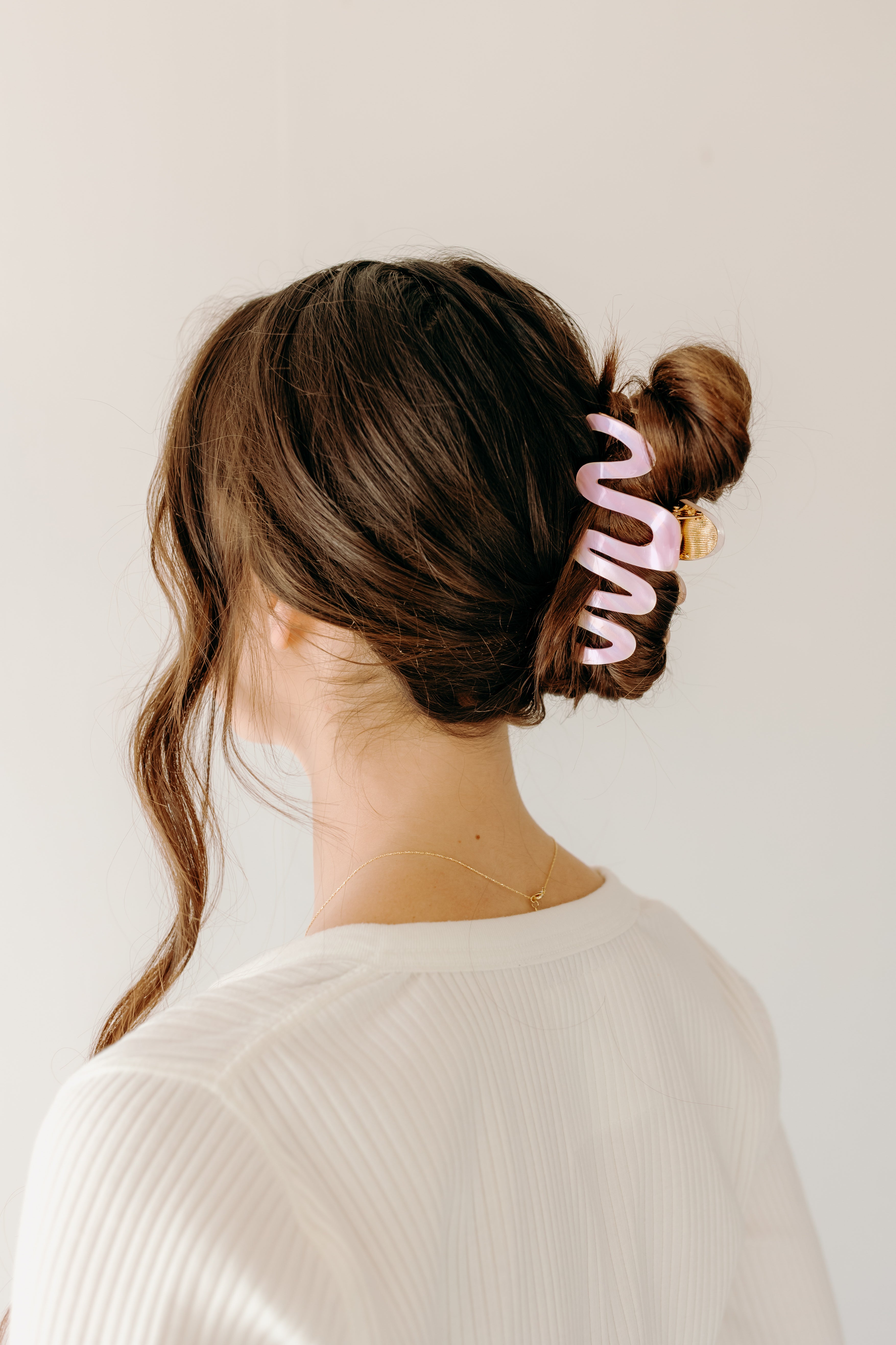 Woman wearing a pink Comes in Waves Lilac Clip hair clip, showcasing her hairstyle.