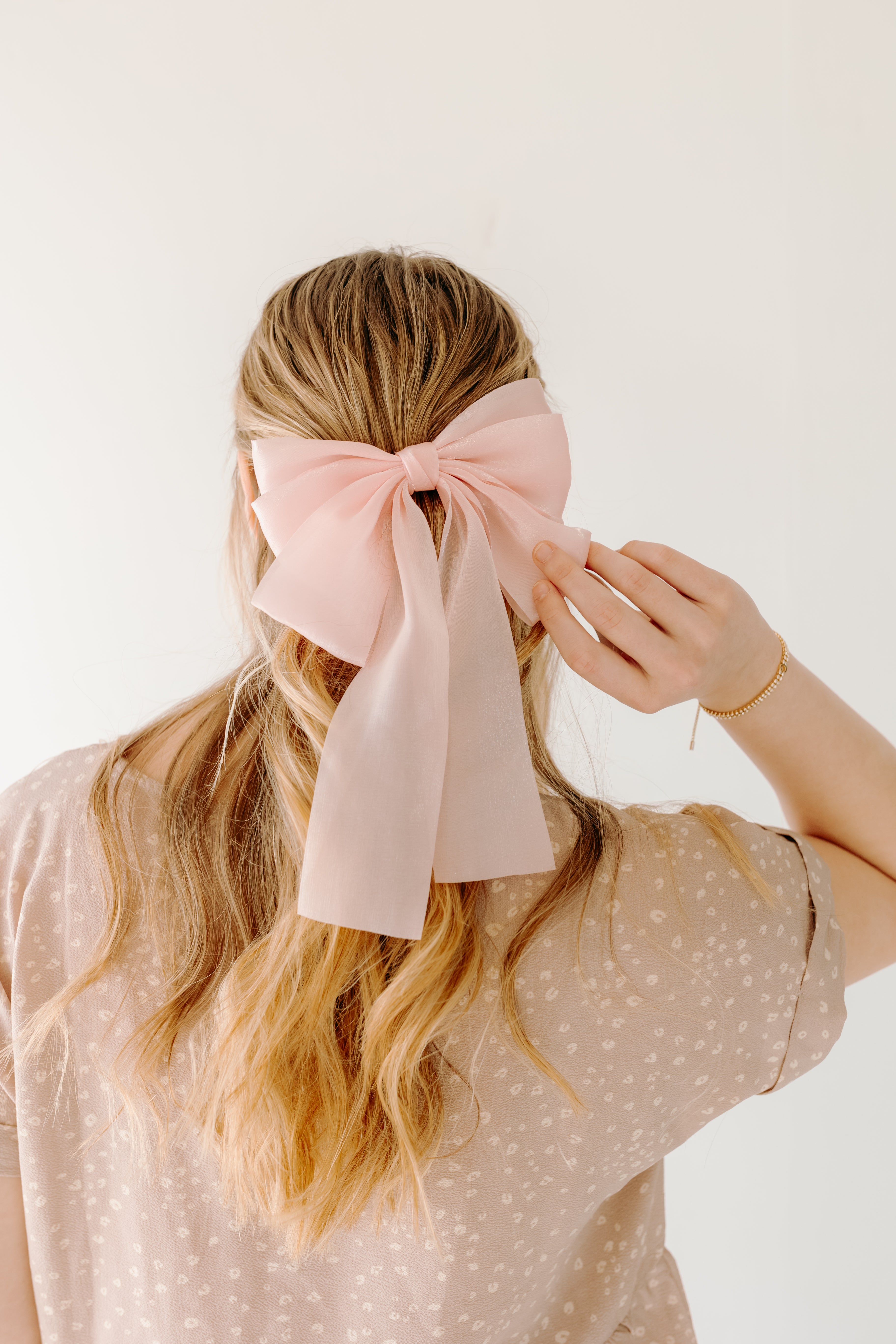Woman wearing Say Less Lilac Clip with pink bow, a cute fashion accessory.