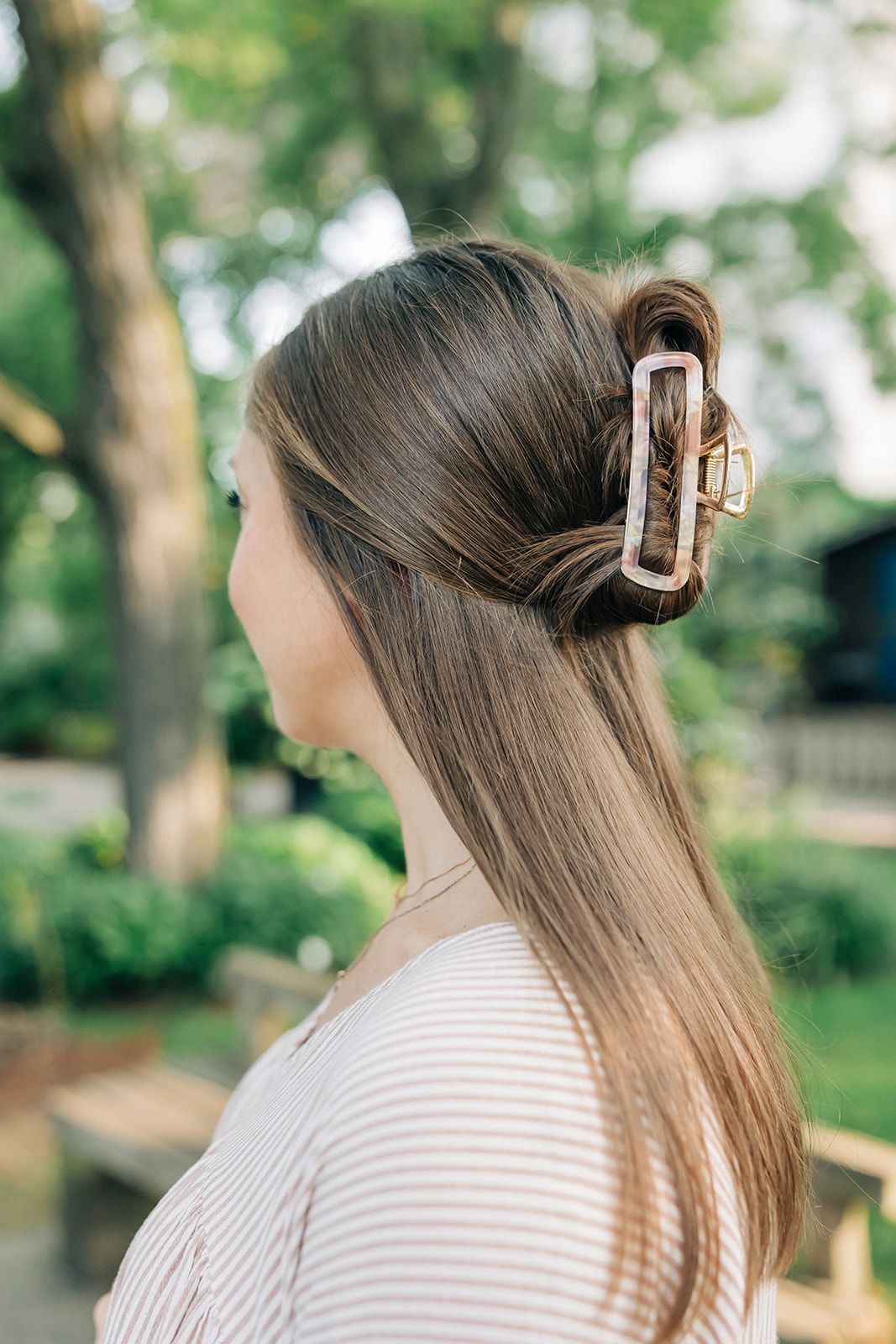 Woman with long hair in a bun, adorned with the Break A Leg Clip from The Sarah Wallace Collection, a marble and metal hair accessory.