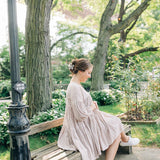 Woman outdoors with a white flower Central Park Stroll Clip. Holding her bun securely, her style highlights the clip's marble and metal design.