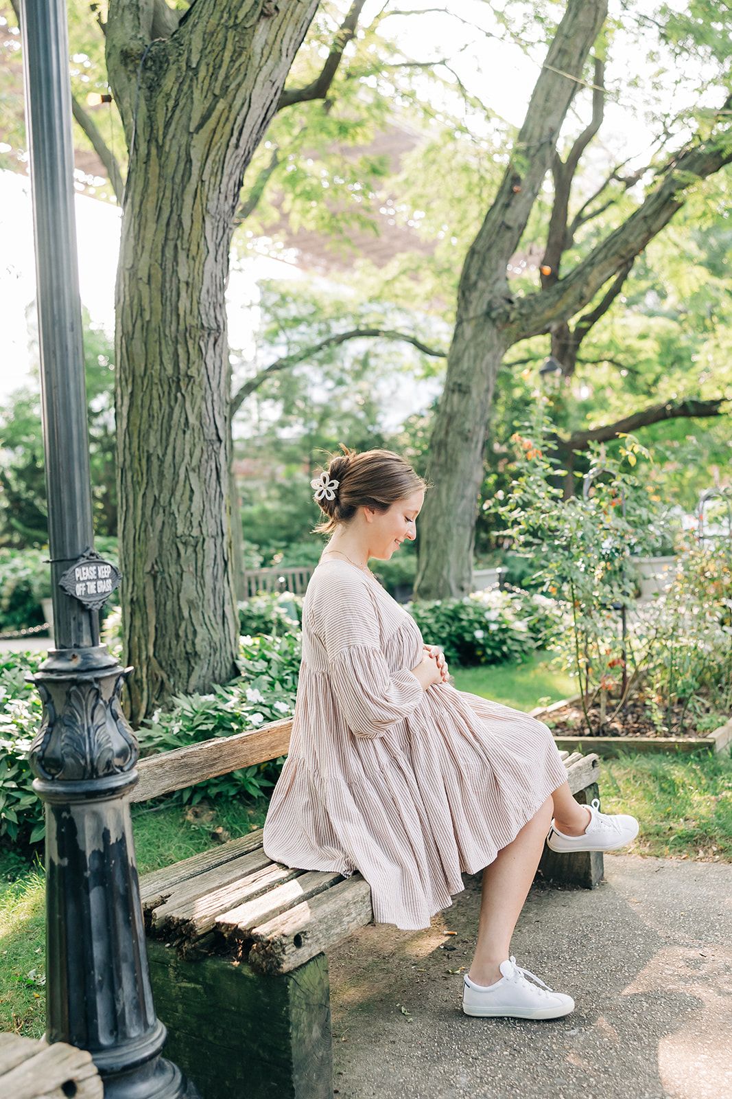 Woman outdoors with a white flower Central Park Stroll Clip. Holding her bun securely, her style highlights the clip's marble and metal design.