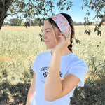 A woman outdoors wearing a Kitchen's Closed Lilac Market Headband, showcasing its versatile twist style and functional design.