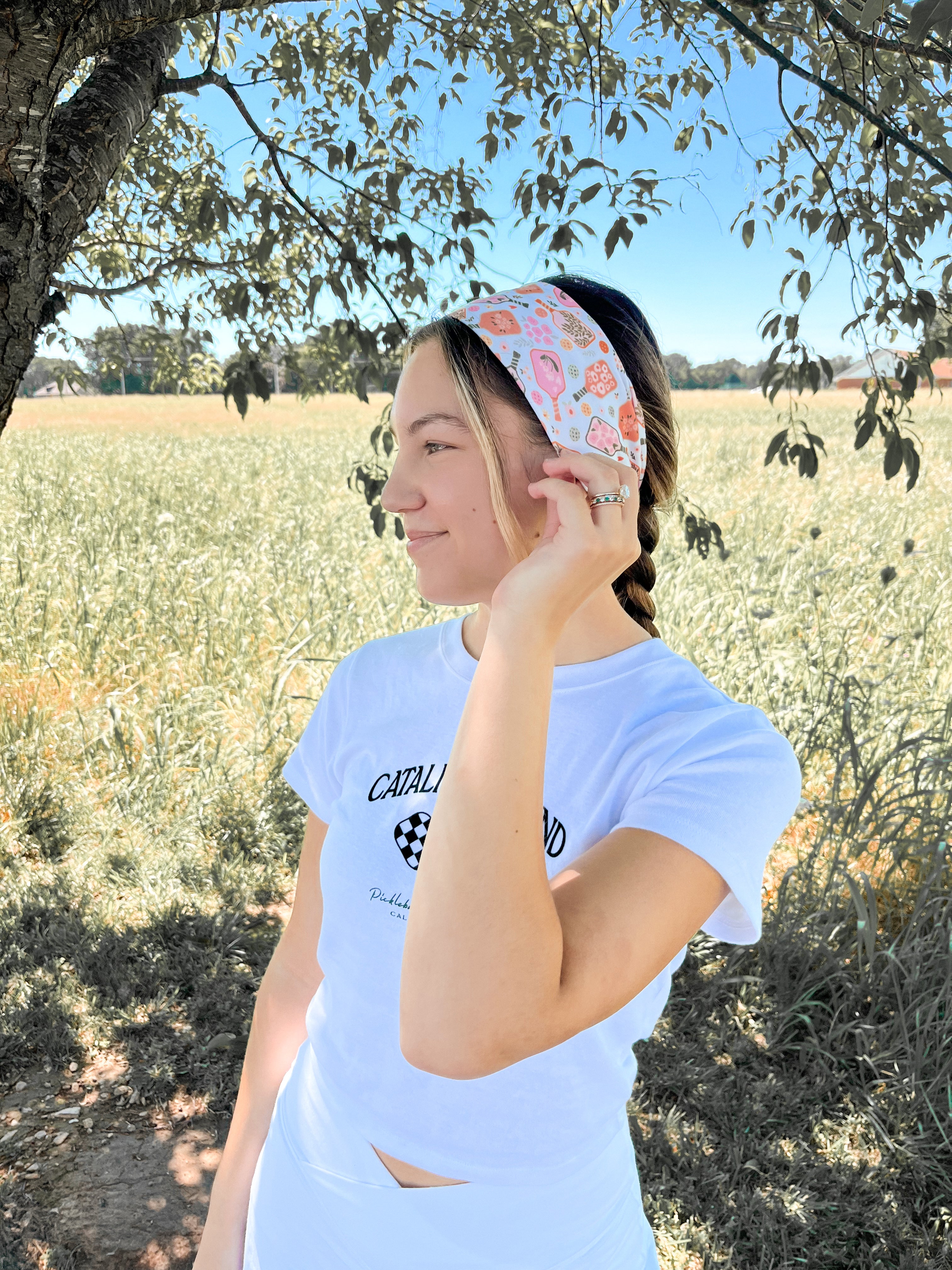 A woman outdoors wearing a Kitchen's Closed Lilac Market Headband, showcasing its versatile twist style and functional design.