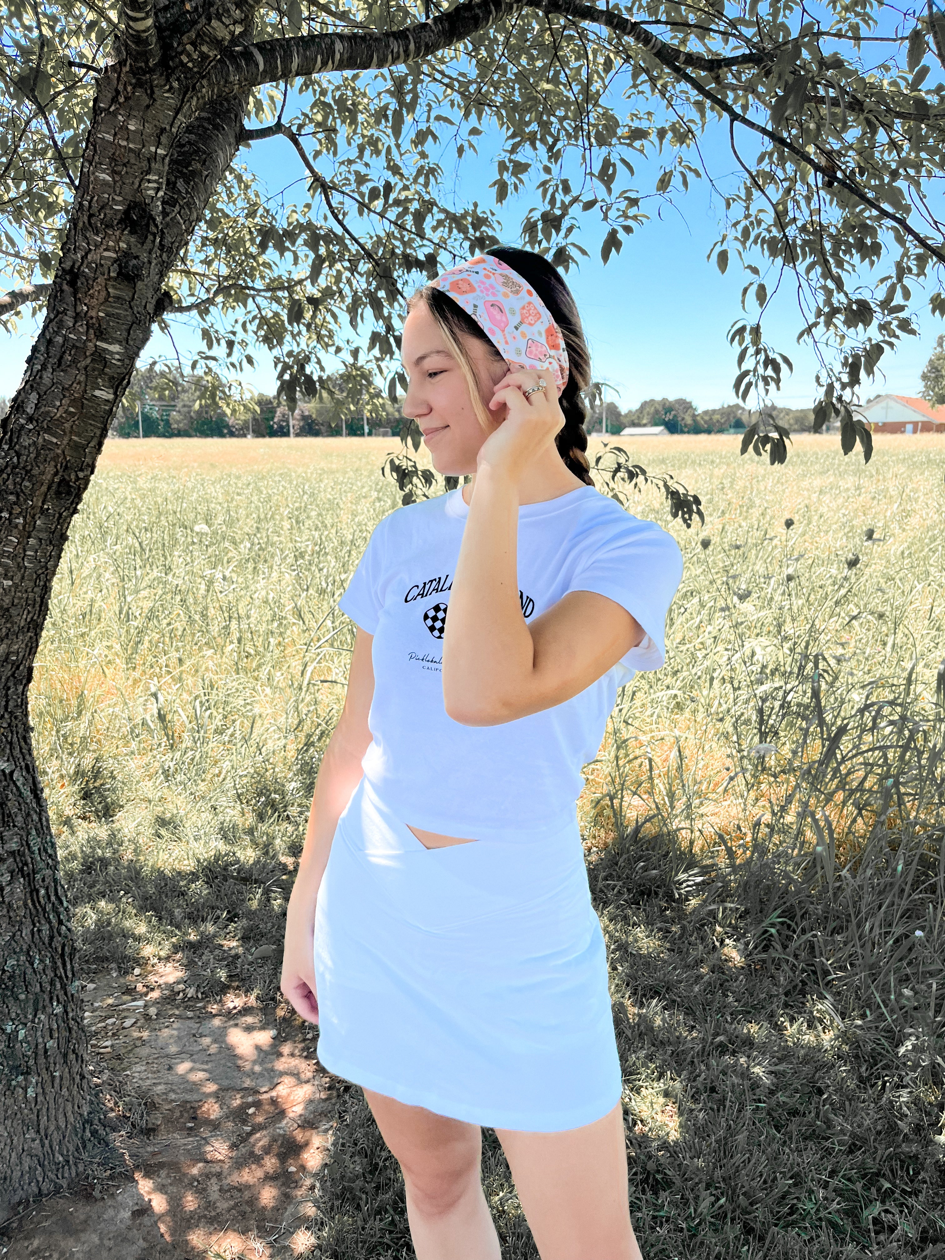 A woman outdoors wearing a Kitchen's Closed Lilac Market Headband, showcasing its versatile twist style and functional design.