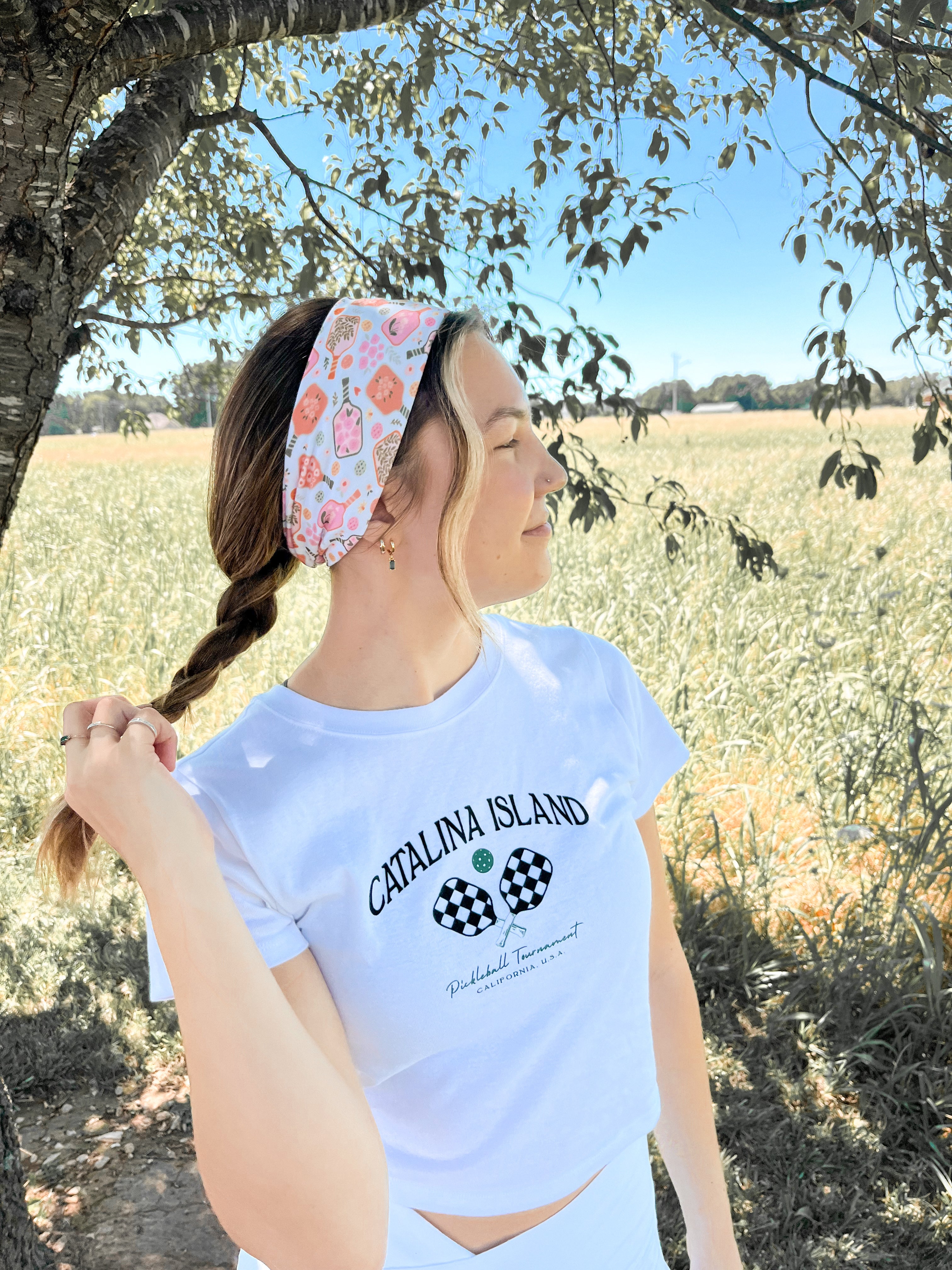 A woman outdoors wearing a Kitchen's Closed Lilac Market Headband, showcasing its versatile twist style and functional design.