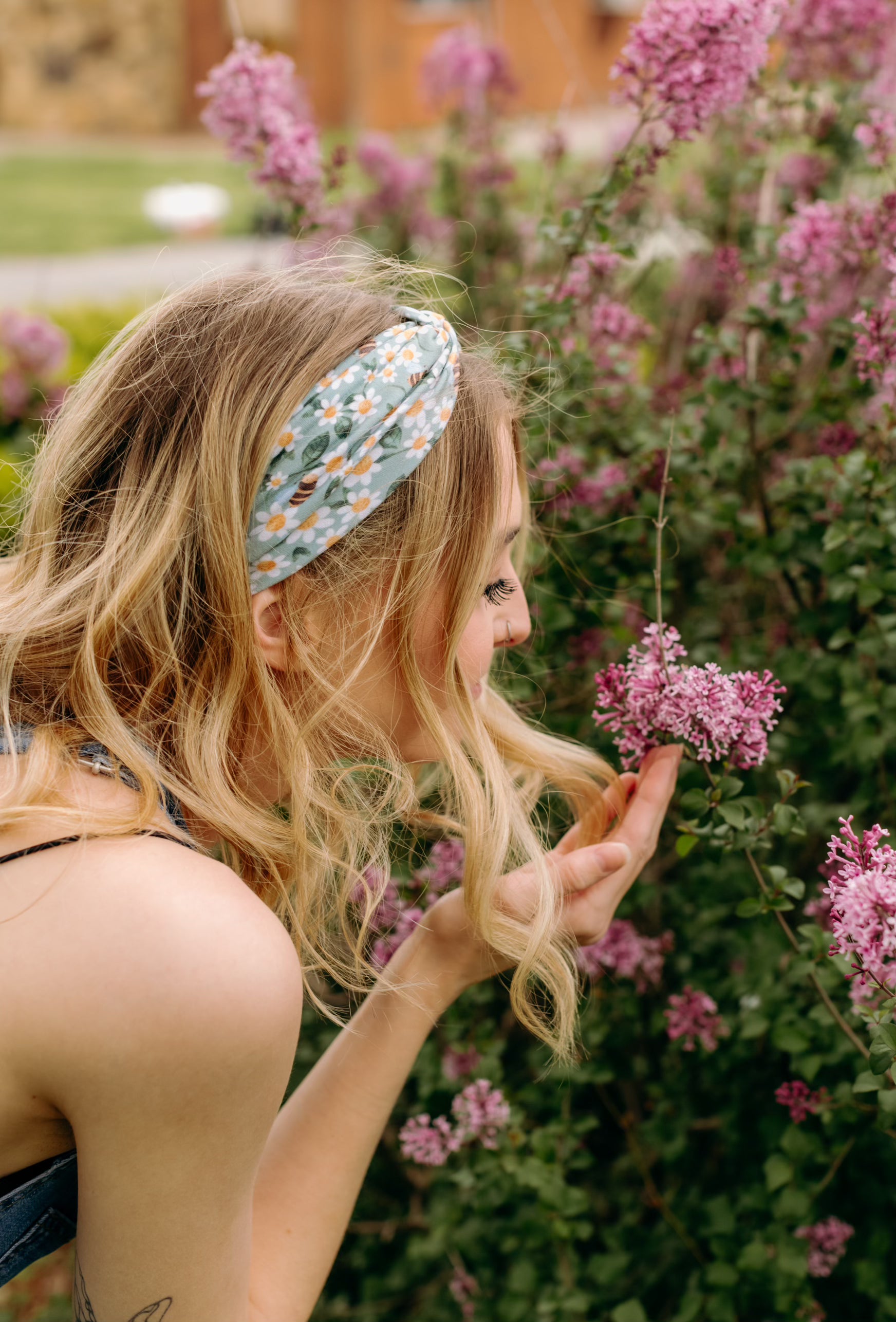 A woman in Lilac Market's Blossom Buddies headband smiles, showcasing its versatile 3-in-1 twist style. Functional, machine washable, and sweat-absorbent for workouts or play.