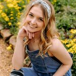 A woman in Lilac Market's Blossom Buddies headband smiles, showcasing its versatile 3-in-1 twist style. Functional, machine washable, and sweat-absorbent for workouts or play.