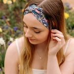 A woman in a Courtney Floral on Navy headband, showcasing a versatile 3-in-1 twist style. Designed for confidence and function, machine washable, sweat-absorbent, and non-slip. Sizes for women and children available.