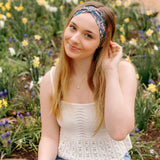 A woman in a Courtney Floral on Navy headband, showcasing a versatile 3-in-1 twist style. Designed for confidence and function, machine washable, sweat-absorbent, and non-slip. Sizes for women and children available.