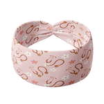 A pink headband with a stethoscope and daisy pattern, designed for confidence and functionality. Features a versatile 3-in-1 twist style, sweat-absorbent double-layer fabric, and a buttery-soft poly-knit blend.