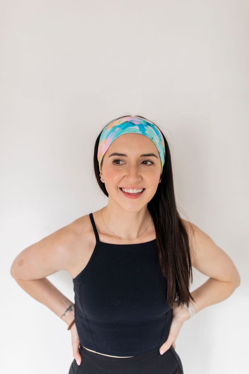 Adult women’s headband with allover layered watercolor paint brushstroke print in varying oranges, pinks, yellows, blues, greens and whites.