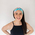 Adult women’s headband with allover layered watercolor paint brushstroke print in varying oranges, pinks, yellows, blues, greens and whites.