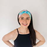 Adult women’s headband with allover layered watercolor paint brushstroke print in varying oranges, pinks, yellows, blues, greens and whites.