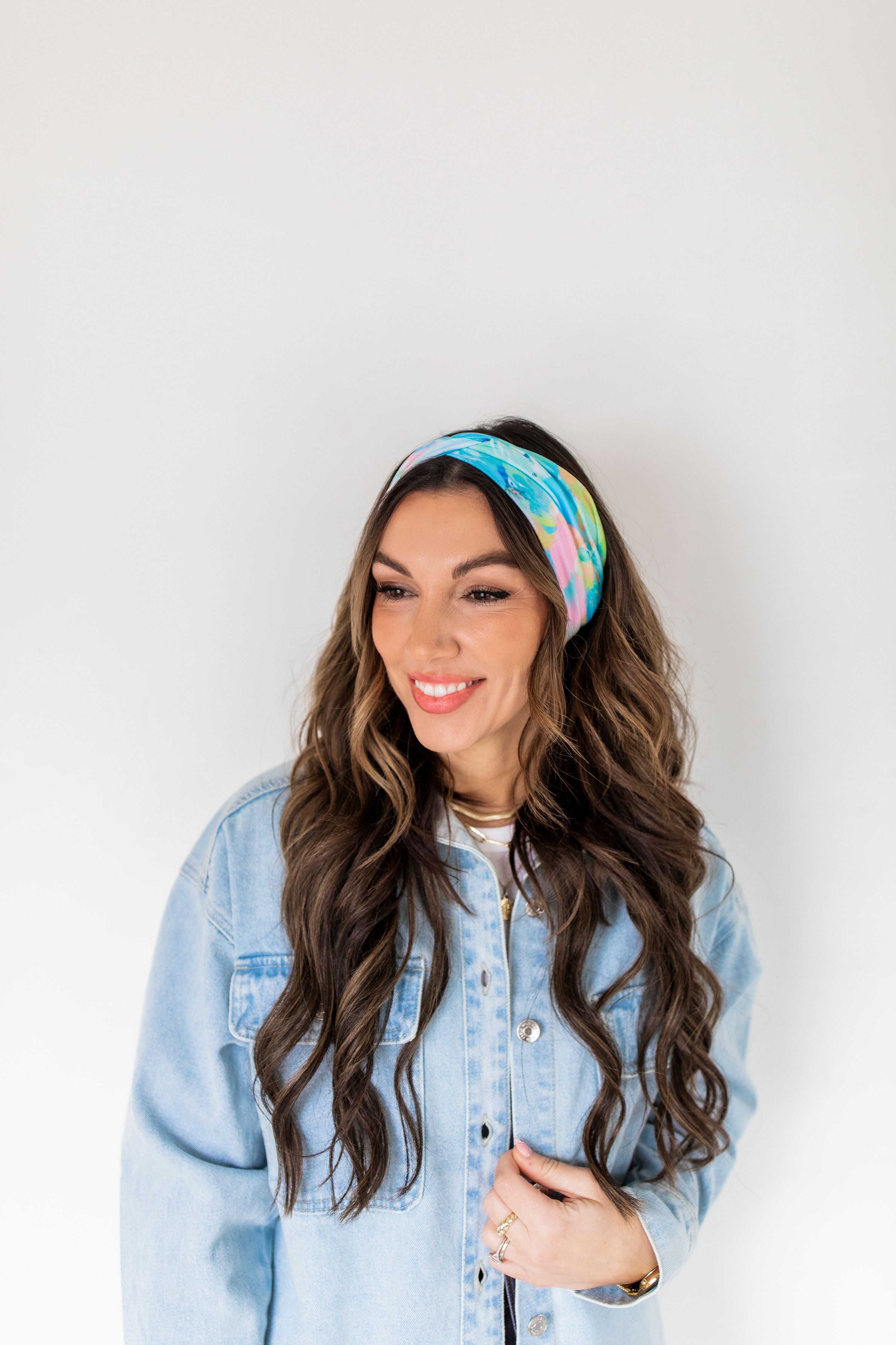 Adult women’s headband with allover layered watercolor paint brushstroke print in varying oranges, pinks, yellows, blues, greens and whites.