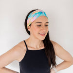 Adult women’s headband with allover layered watercolor paint brushstroke print in varying oranges, pinks, yellows, blues, greens and whites.