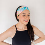 Adult women’s headband with allover layered watercolor paint brushstroke print in varying oranges, pinks, yellows, blues, greens and whites.