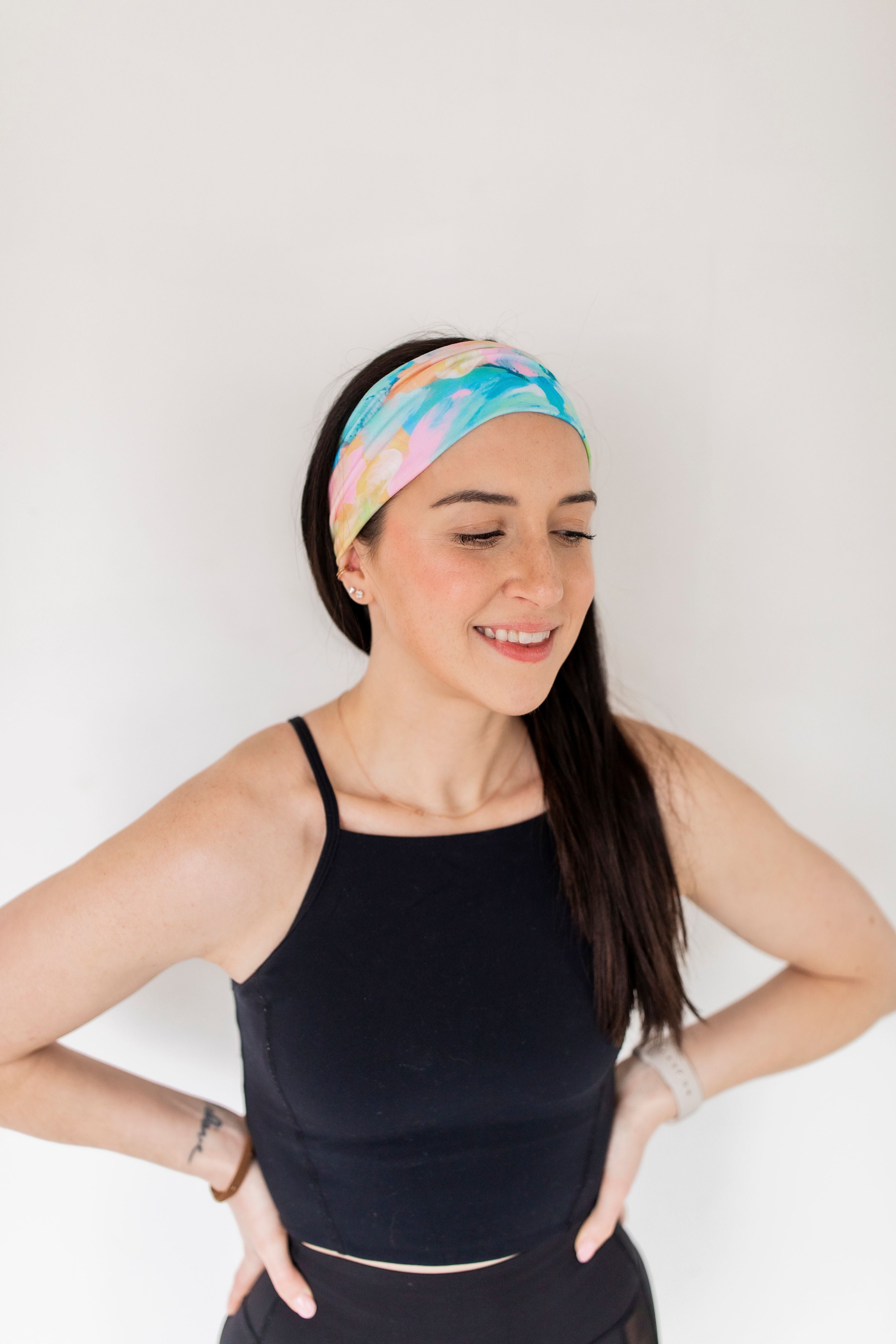 Adult women’s headband with allover layered watercolor paint brushstroke print in varying oranges, pinks, yellows, blues, greens and whites.