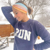 Adult women's gradient headband with yellow, orange and blue with allover white shoe prints, three yellow, orange and white horizontal lines and the white script saying "enjoy the miles"