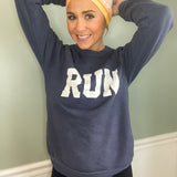 Adult women's gradient headband with yellow, orange and blue with allover white shoe prints, three yellow, orange and white horizontal lines and the white script saying "enjoy the miles"