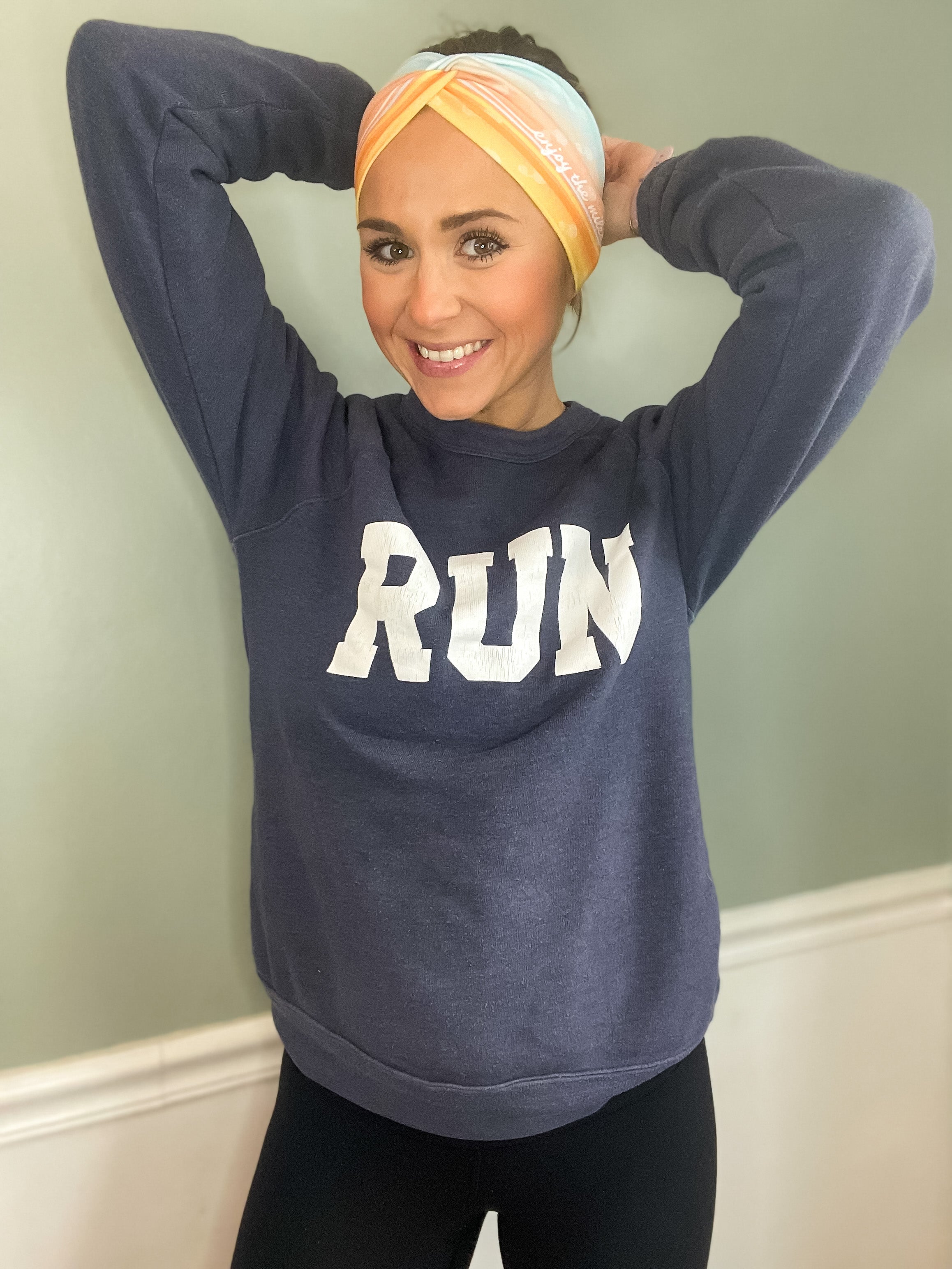 Adult women's gradient headband with yellow, orange and blue with allover white shoe prints, three yellow, orange and white horizontal lines and the white script saying "enjoy the miles"