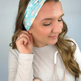 Adult women's blue-teal headband with yellow smiley faces, pink daisies, muted rainbows, and pink stethoscopes with a heart on the end