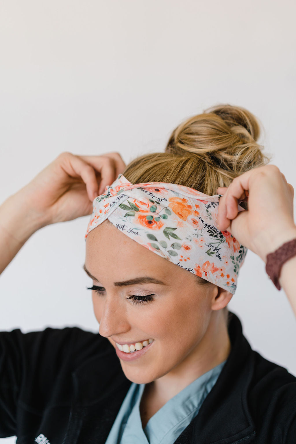 Adult women's ivory headband with watercolor coral, orange, peach and ivory flowers and leaves with the cursive script "I've got you" hidden throughout the print