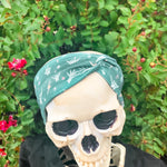 Adult women's emerald green headband with skeleton hands signing love, peace, rock-on and hang-loose shaka sign with yellow lightneing bolts and orange and pink diamonds