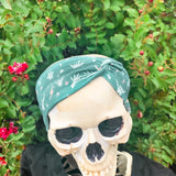 Adult women's emerald green headband with skeleton hands signing love, peace, rock-on and hang-loose shaka sign with yellow lightneing bolts and orange and pink diamonds